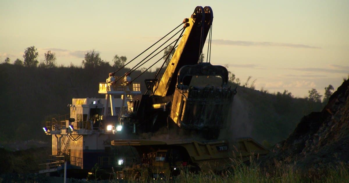 Pala eléctrica cargando un camión minero al atardecer en la mina Dawson, cerca de Moura, en el centro de Queensland