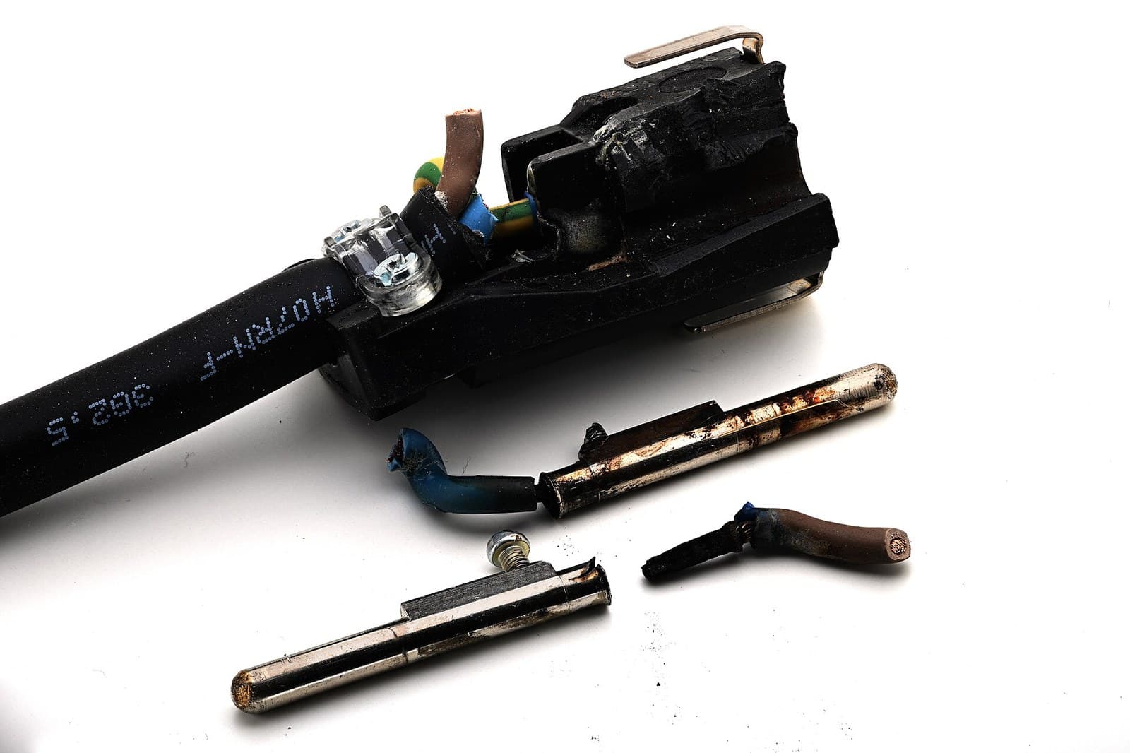 Fotografía real de un cable flexible sobrecargado con aislamiento y clavija carbonizados por calentamiento resistivo excesivo