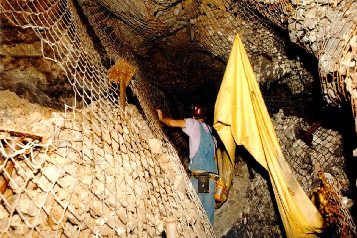 Brazo articulado de jumbo empernador instalando anclajes y pernos helicoidales en bóveda