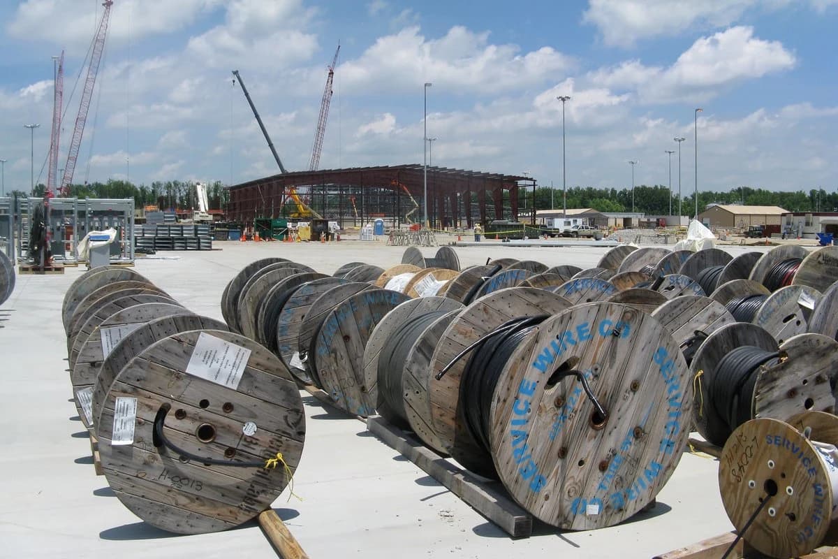 Inspección de recepción de carretes de cables mineros de potencia en patio de almacén verificando placas metálicas y sellos de trazabilidad