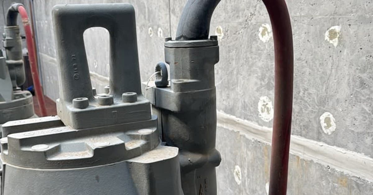 Top of a submersible pump with its lifting handle and cable entry, where the red supply cable meets a black bend