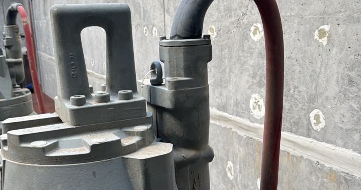 Top of a submersible pump with its lifting handle and cable entry, where the red supply cable meets a black bend